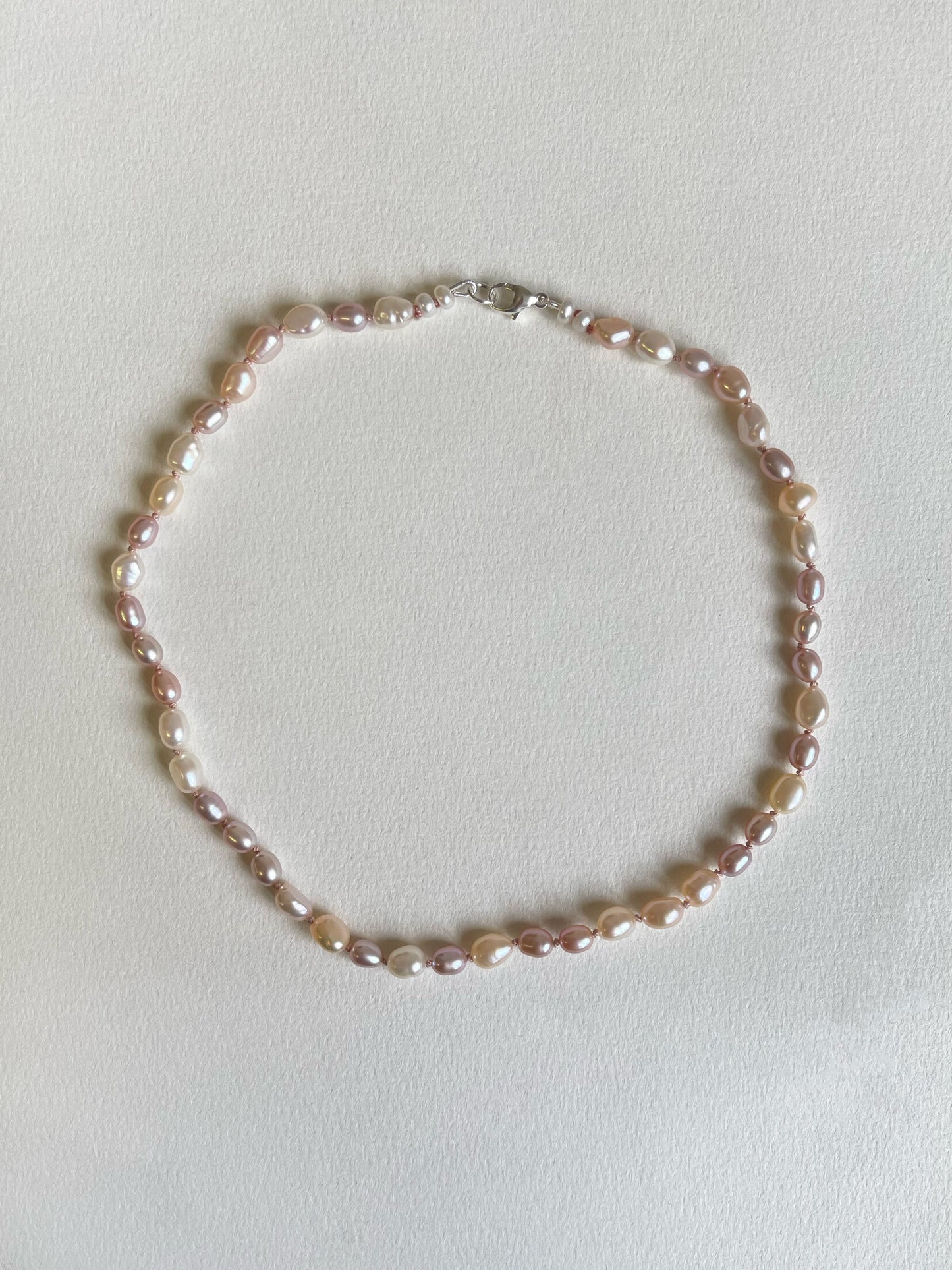Pink and white pearl necklace on a light background