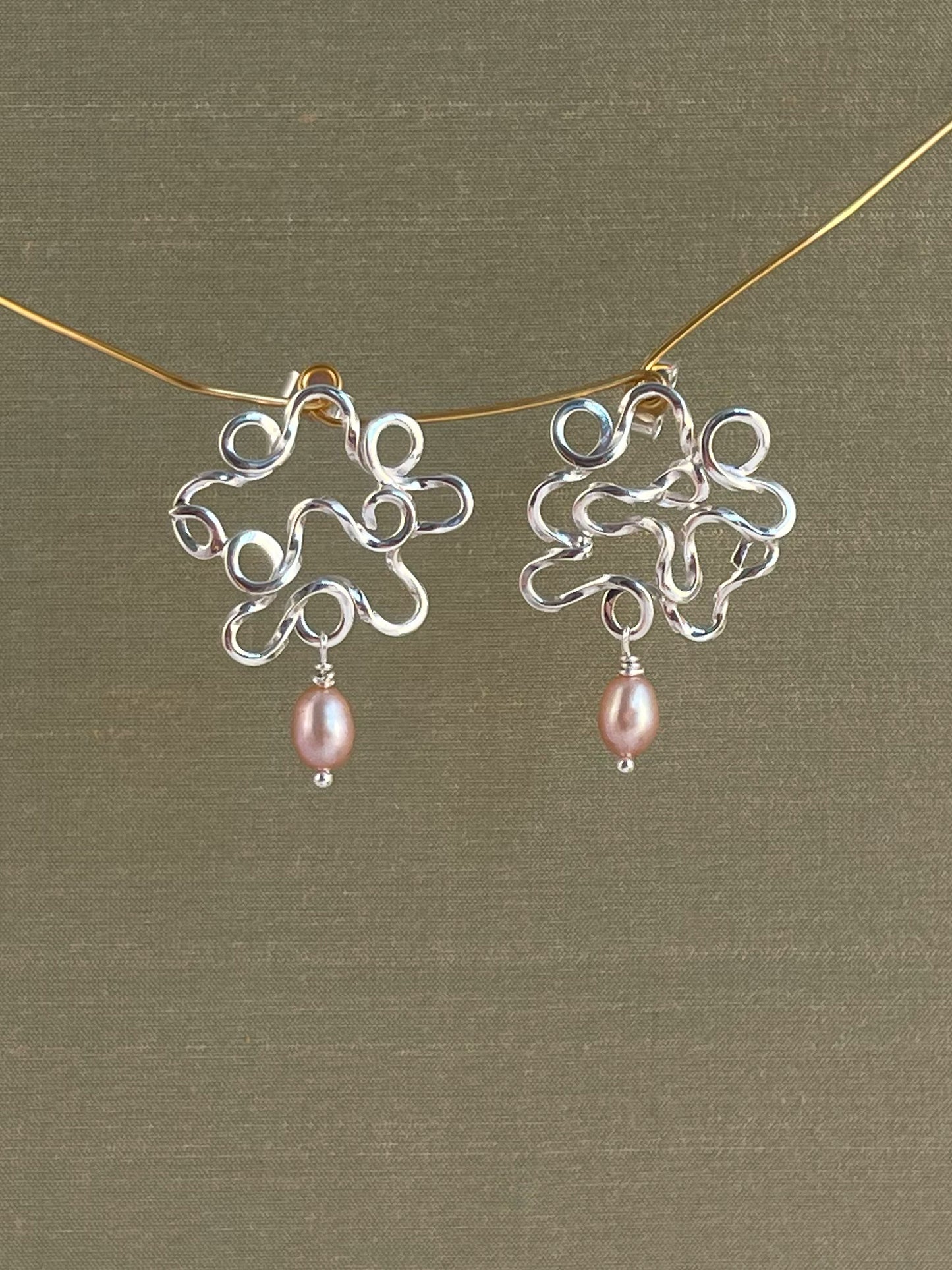 Silver earrings with pink pearls on a green background