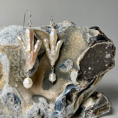 Silver dangly earrings with a white pearl in the shape of a claw with a white pearl beneath