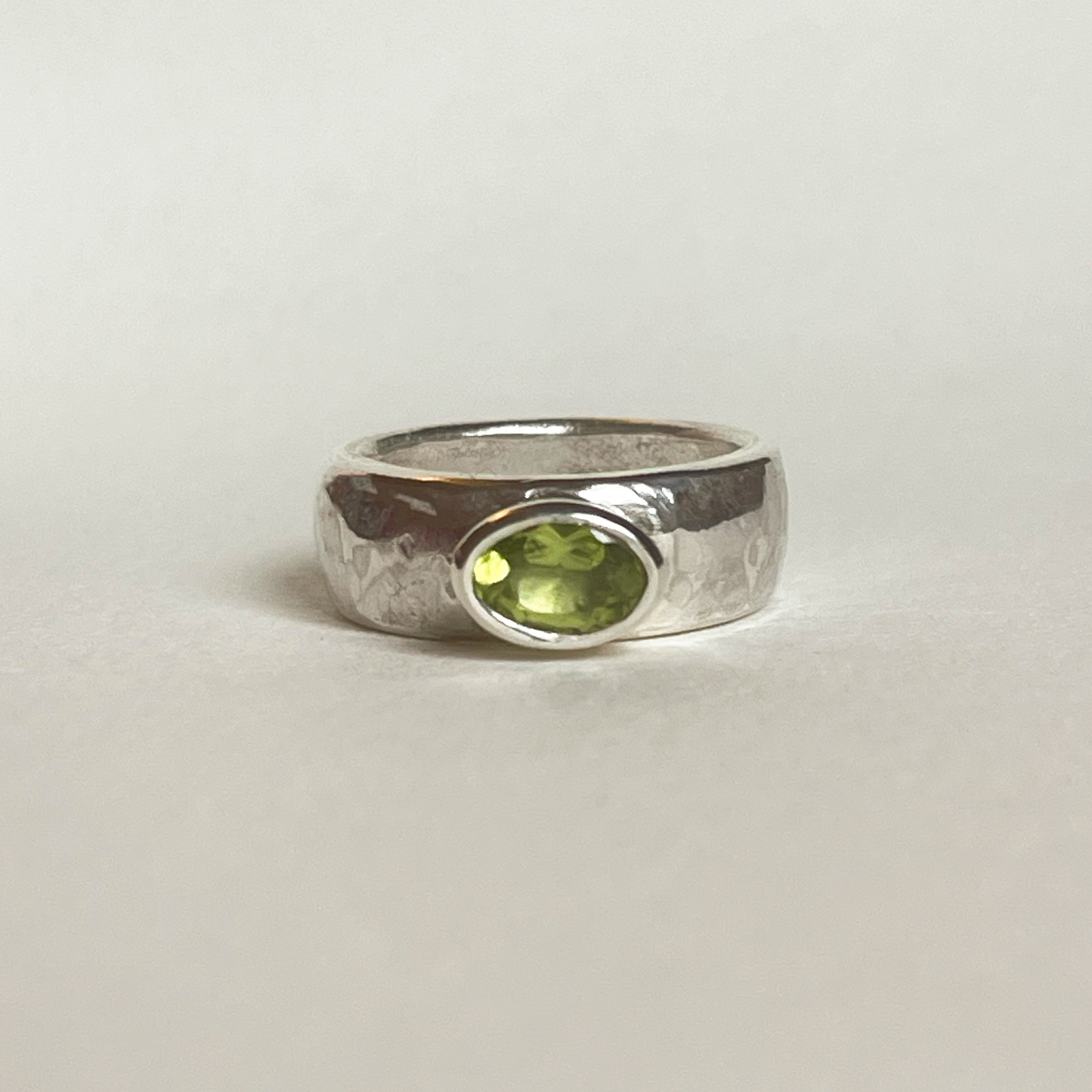 Chunky silver ring with a green peridot on a light background