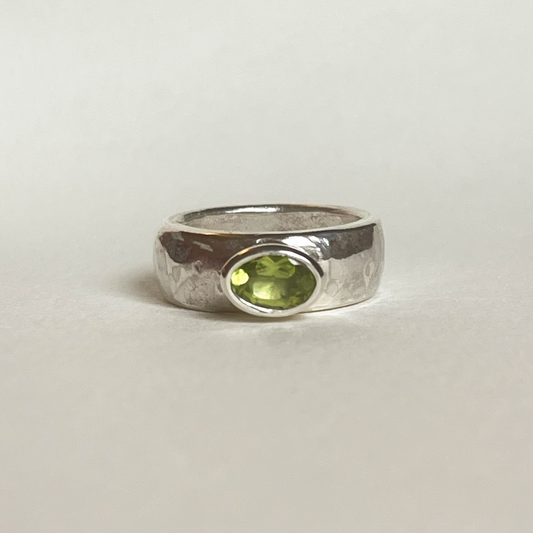 Chunky silver ring with a green peridot on a light background
