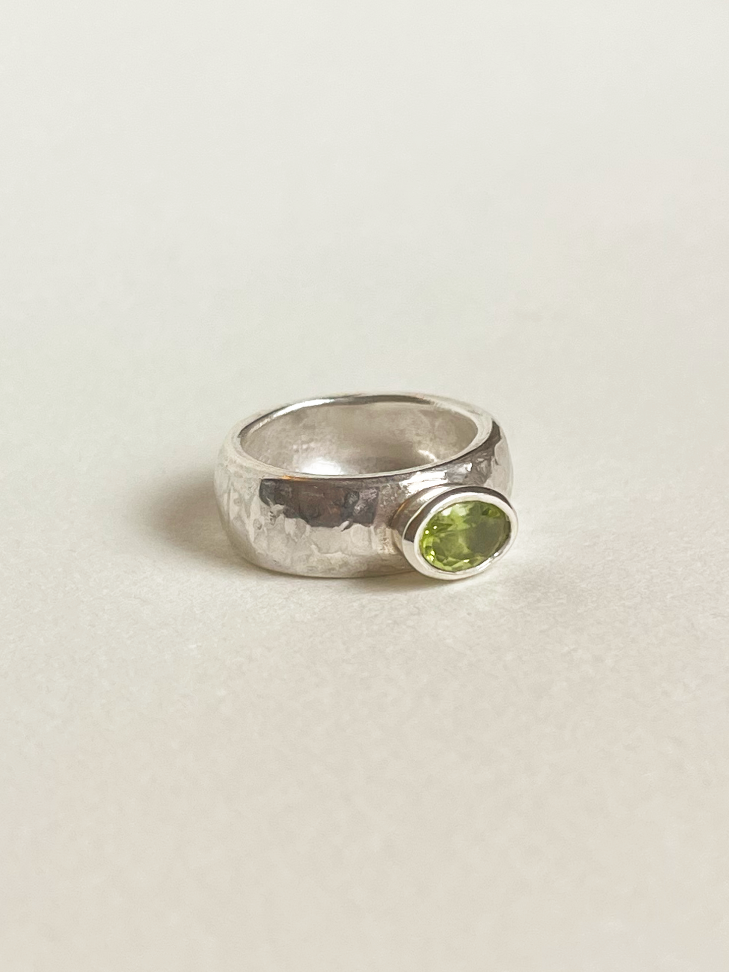 Chunky silver ring with a green peridot on a light background