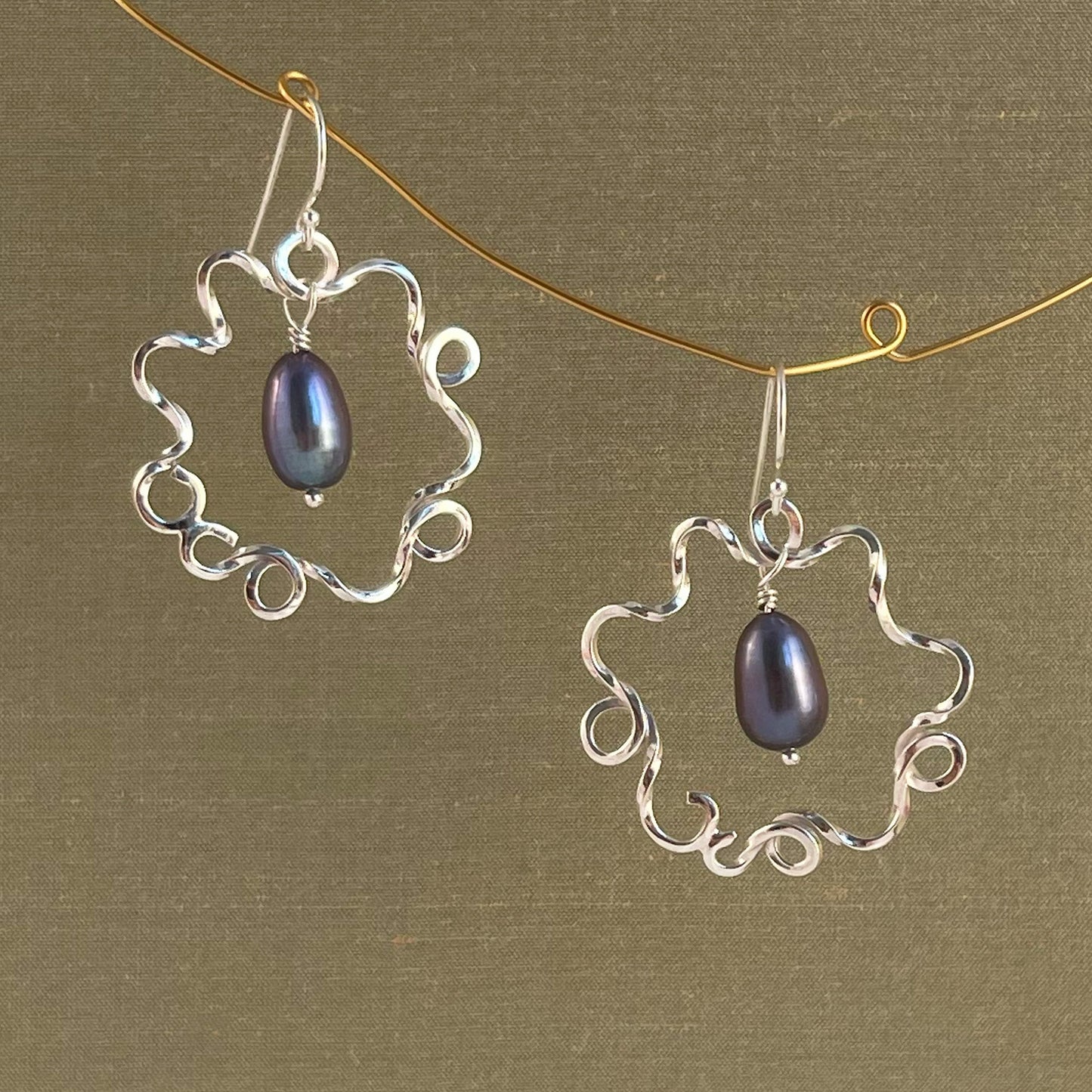 Silver earrings with blue pearl on a green background