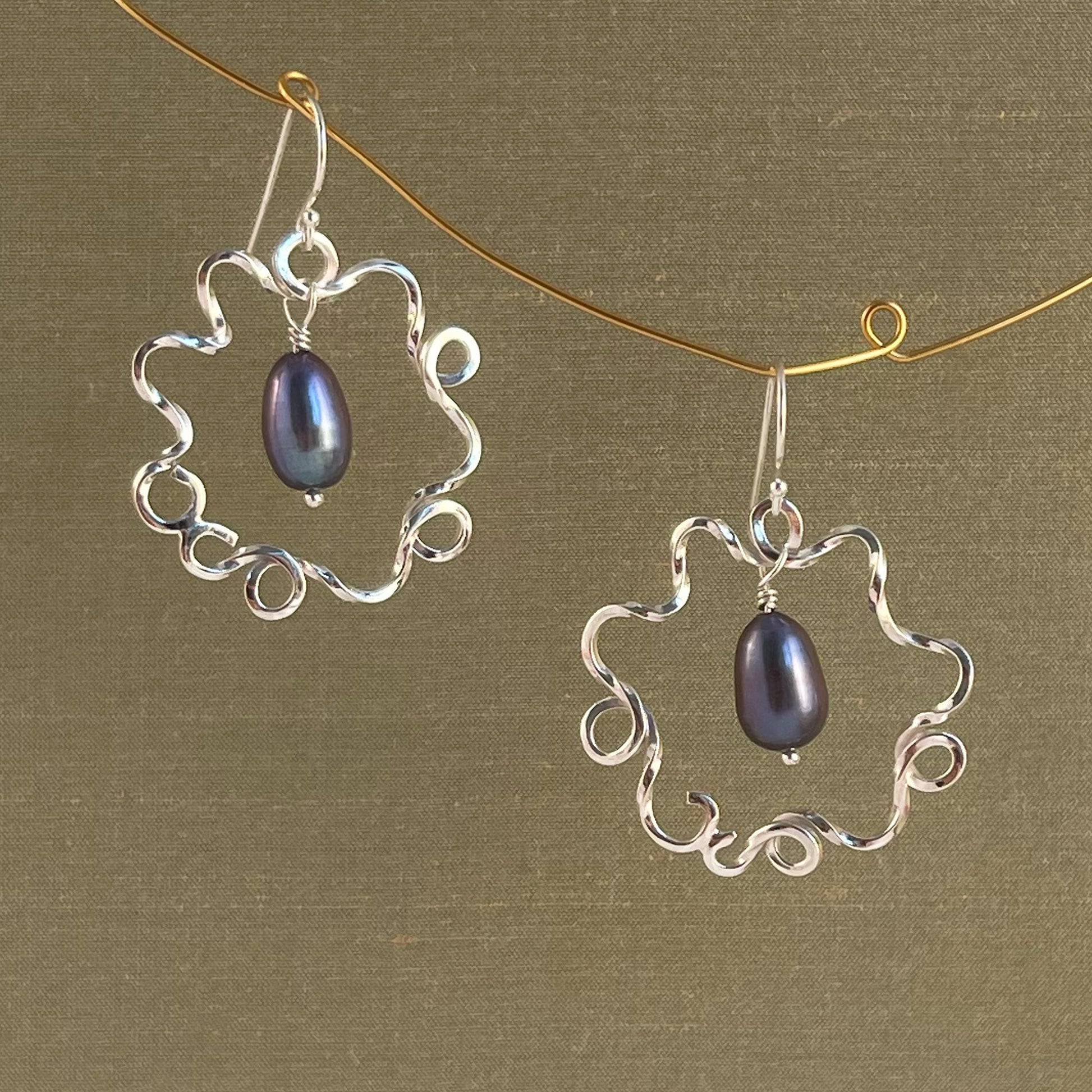 Silver earrings with blue pearl on a green background