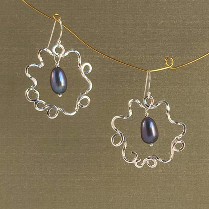 Silver earrings with blue pearl on a green background