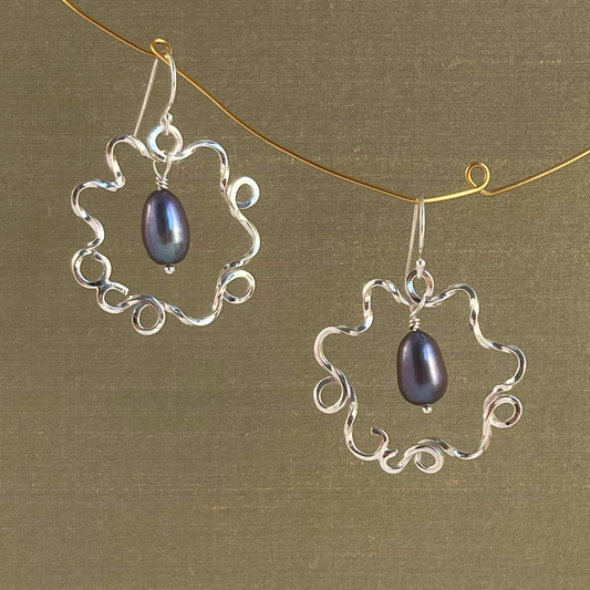 Silver earrings with blue pearl on a green background
