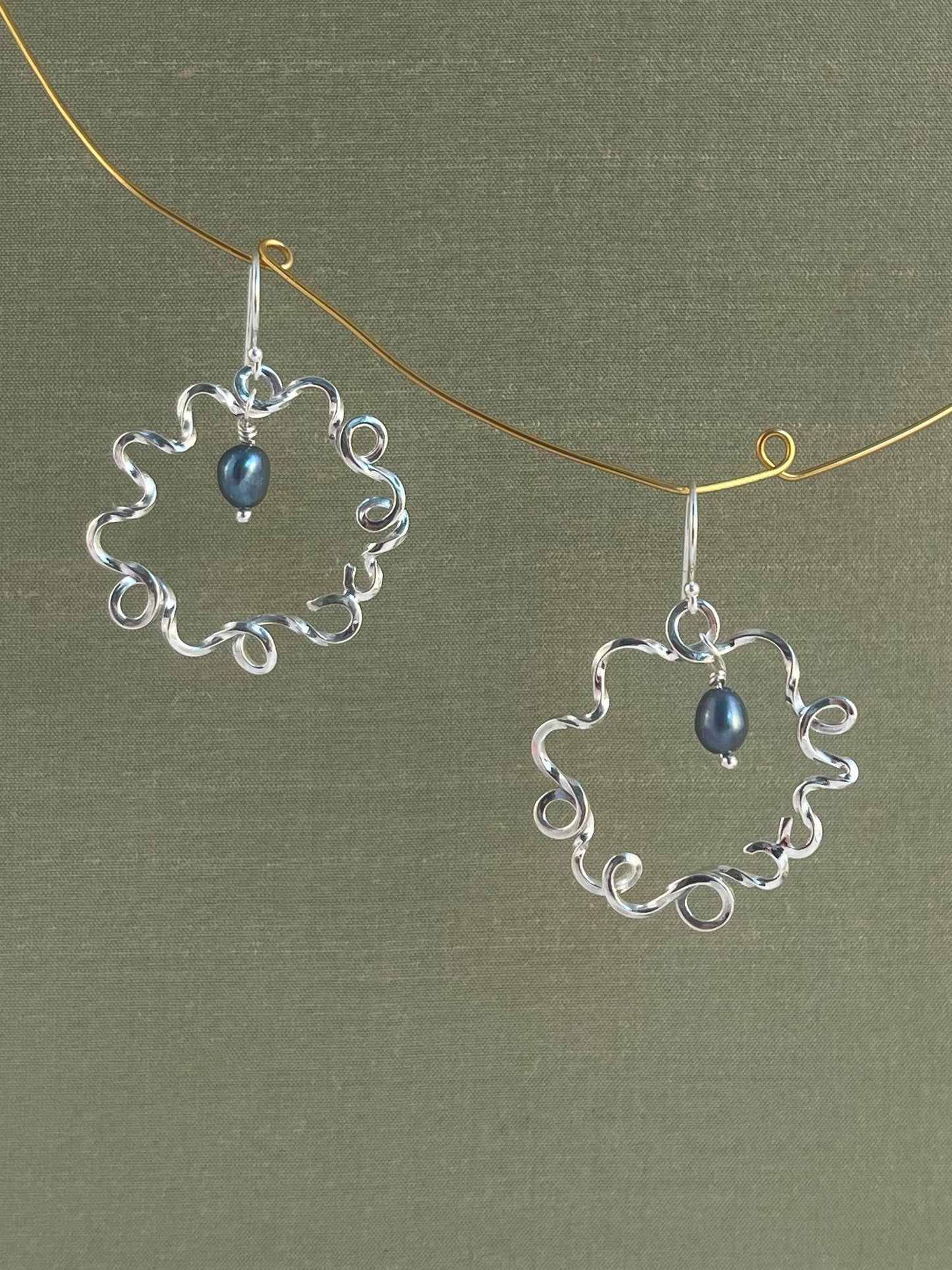 Silver earrings with blue pearls on a green background