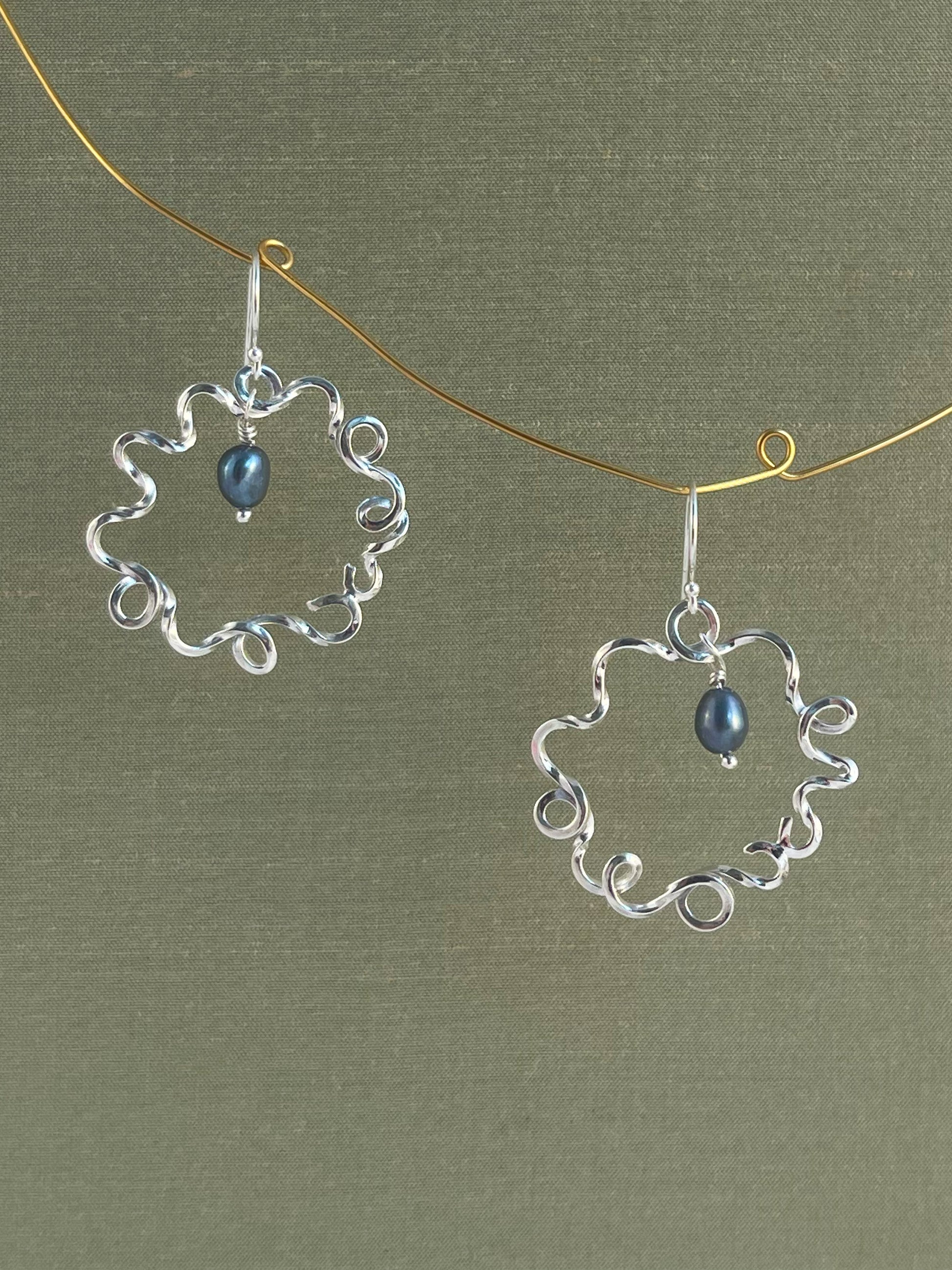 Silver earrings with blue pearls on a green background