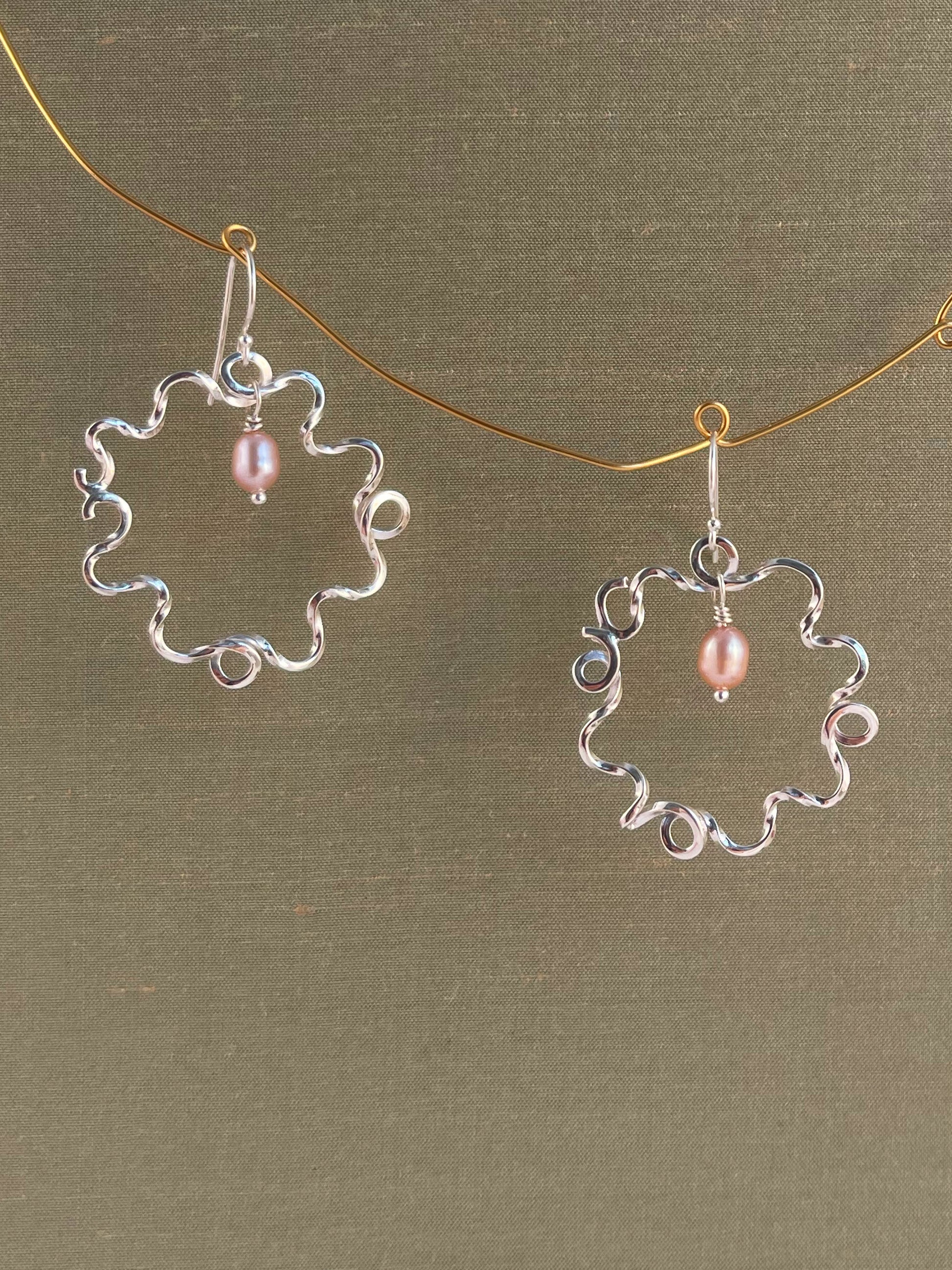Silver earrings with pink pearls on a green background