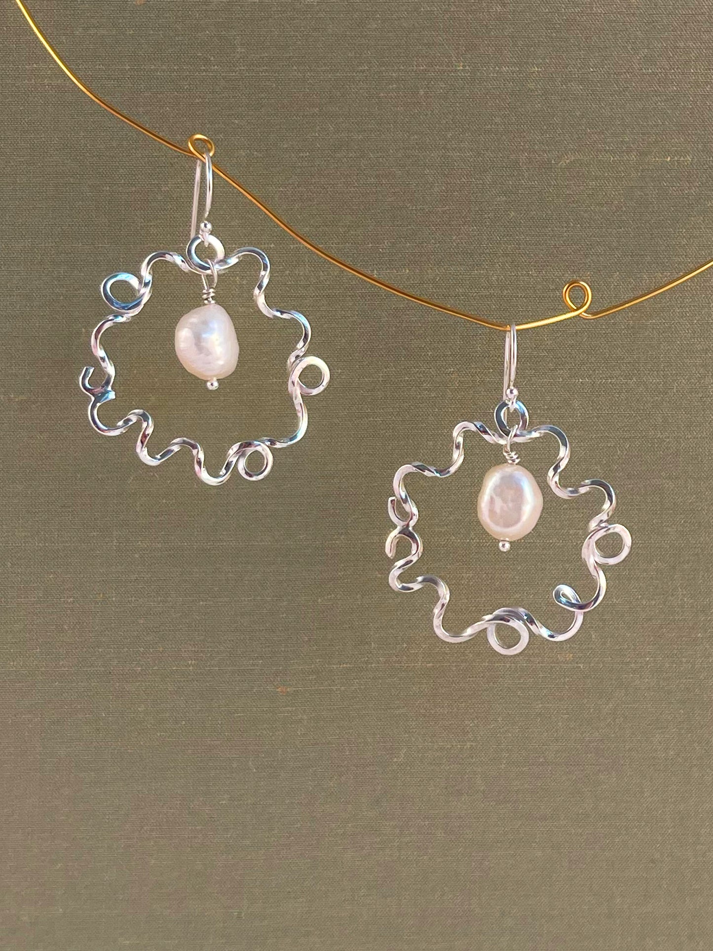 Silver earrings with pearl drops on a green background