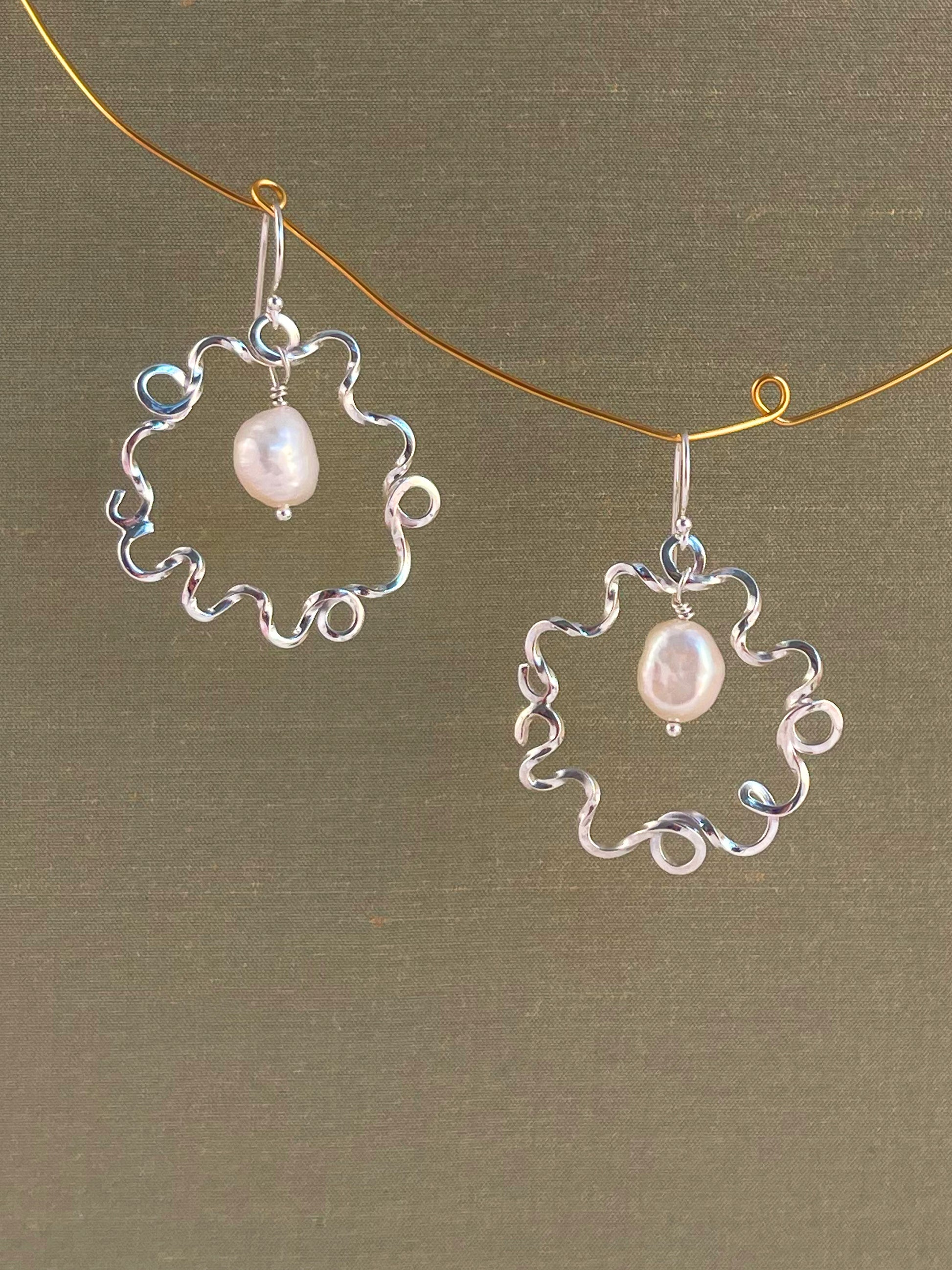 Silver earrings with pearl drops on a green background
