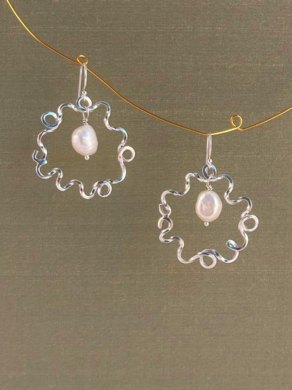 Silver earrings with pearl drops on a green background