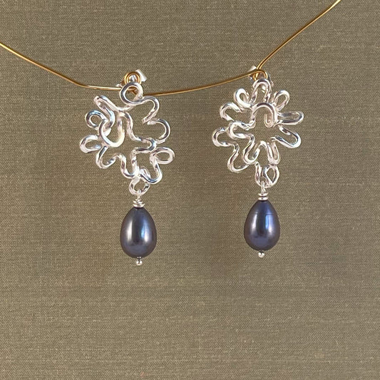 Silver earrings with blue Pearl on a gold chain against a green background