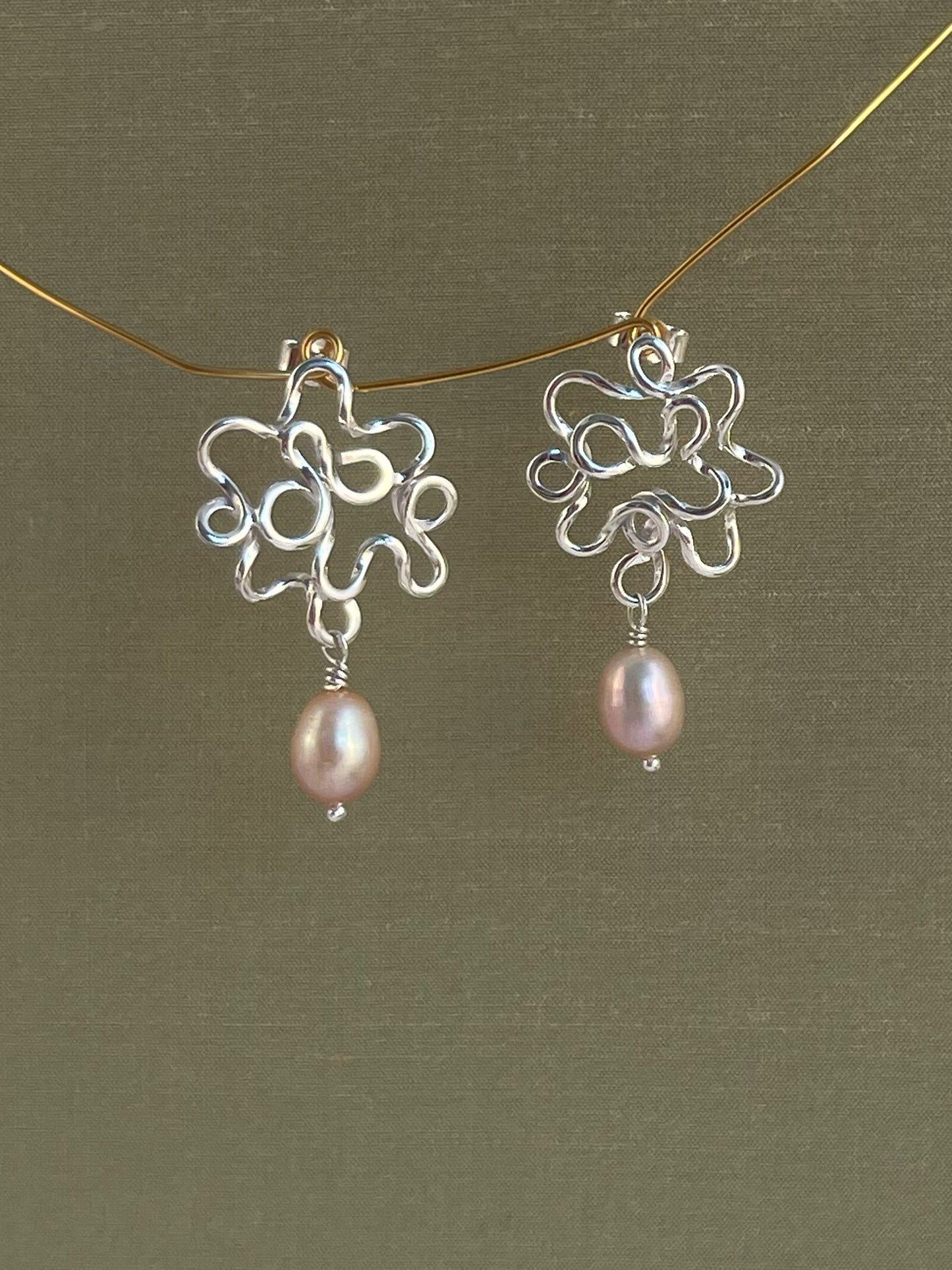 Silver earrings with pink pearls on a green background