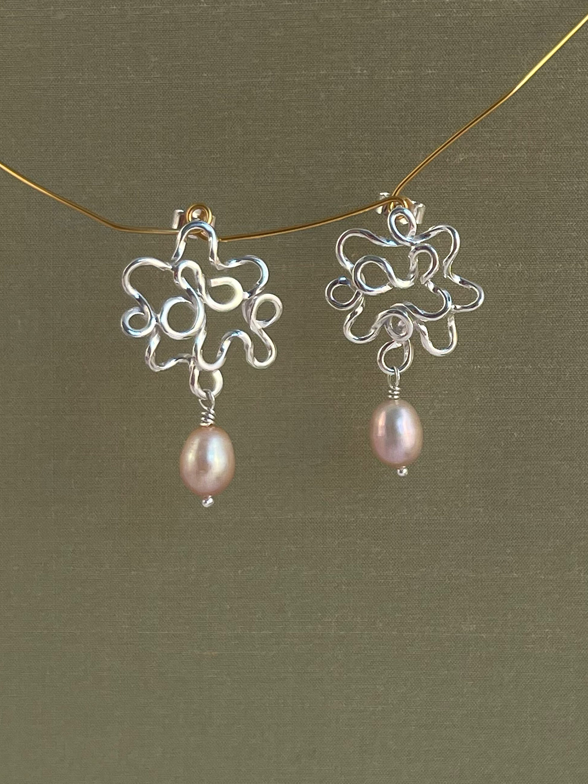 Silver earrings with pink pearls on a green background