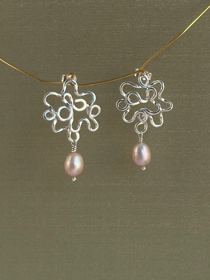 Silver earrings with pink pearls on a green background