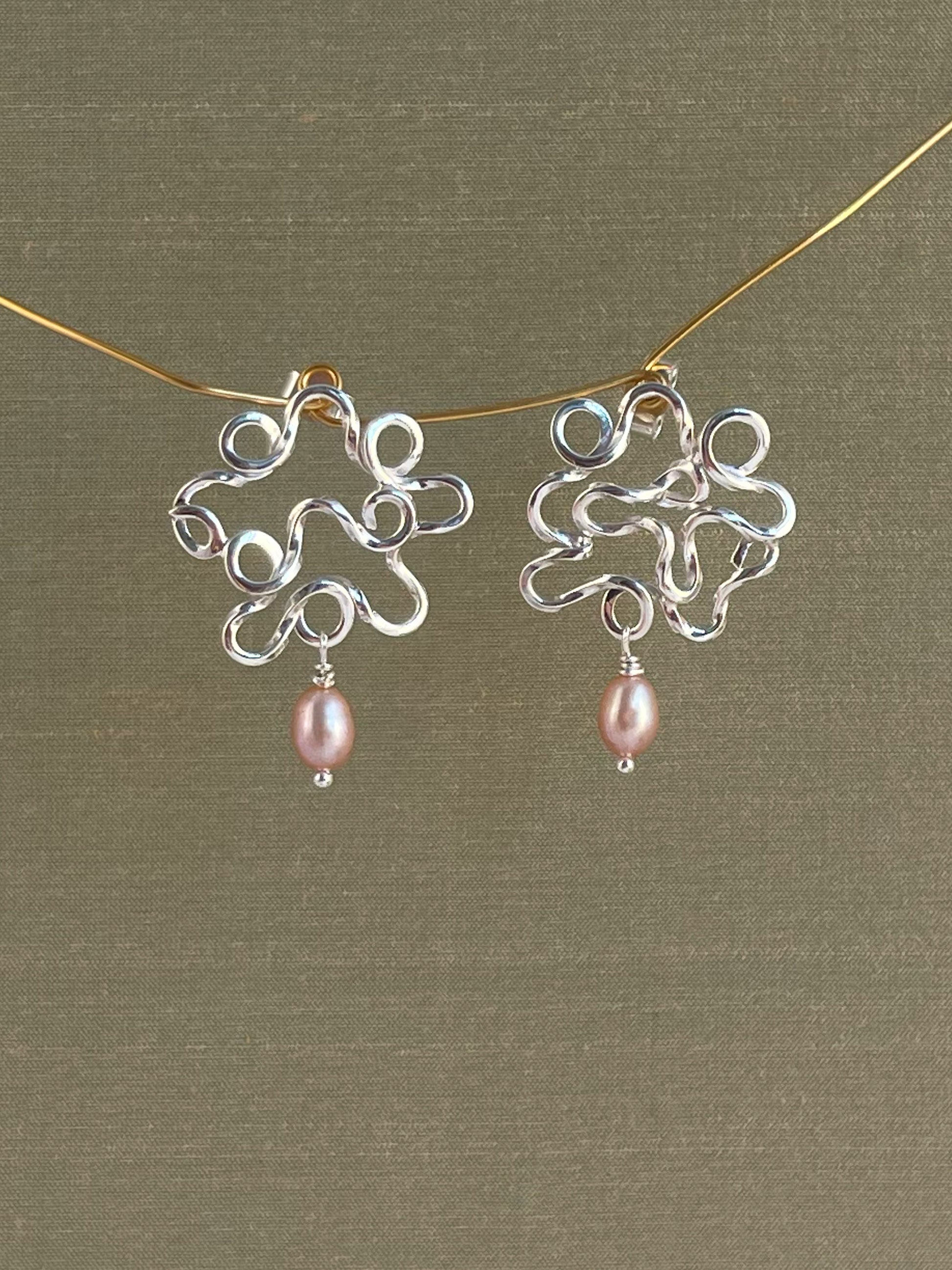 Silver earrings with pink pearls on a green background
