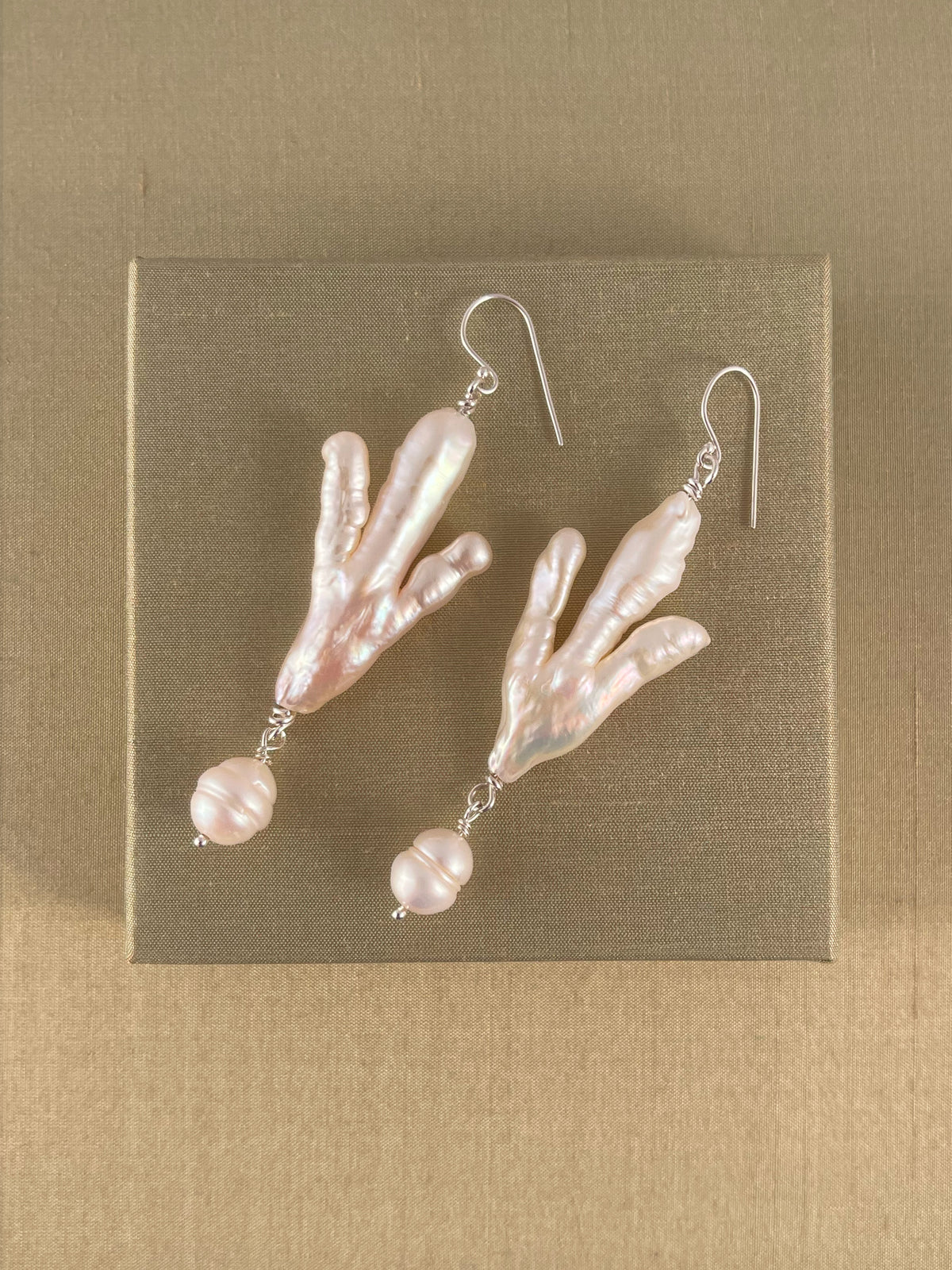 Pair of pearl earrings on a green background