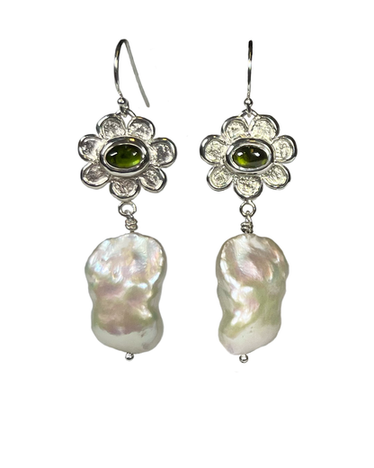 Pair of handmade sterling silver earrings with floral design, and set with green tourmaline and white pearls dangling, on a white background